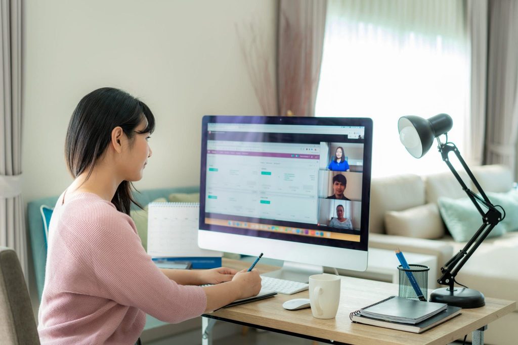 Woman working from home, sitting at her desk on a conference meeting online with colleagues